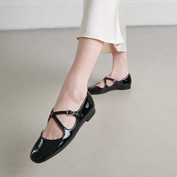 Ballet flats with crossed straps in black patent and ecru leather